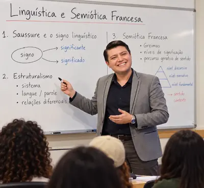 Marcos Costa dando aula de Linguística Aplicada na universidade, apontando para o quadro com o signo de Saussure